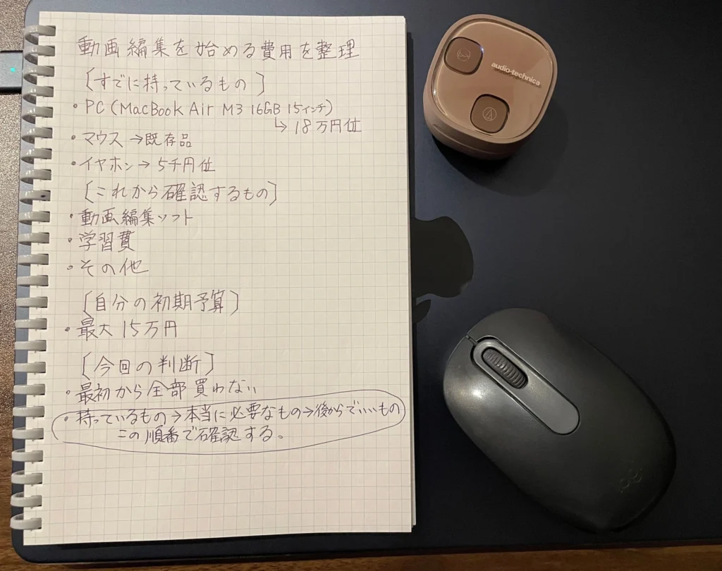 所有している機材、これから確認する費用、初期予算を整理した手書きノートとMac、マウス、イヤホンケース